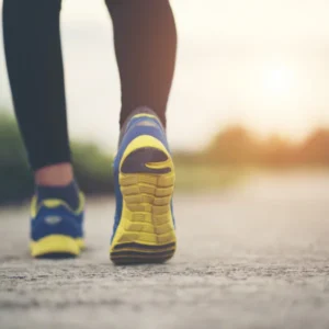 A person walks on a road, wearing yellow and blue shoes.