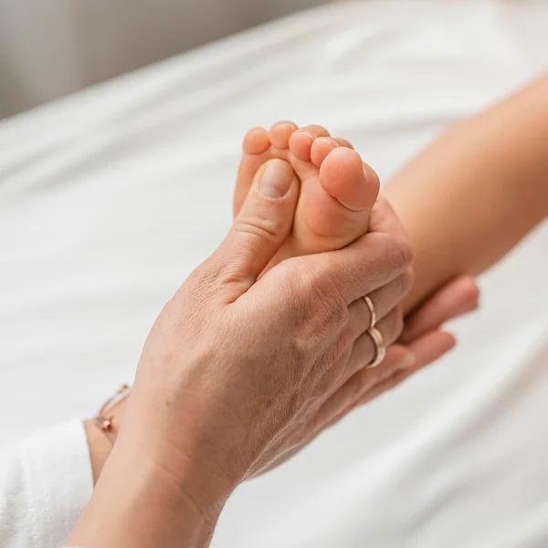 Une personne tient le pied d'un enfant, illustrant un moment de tendresse et de connexion.