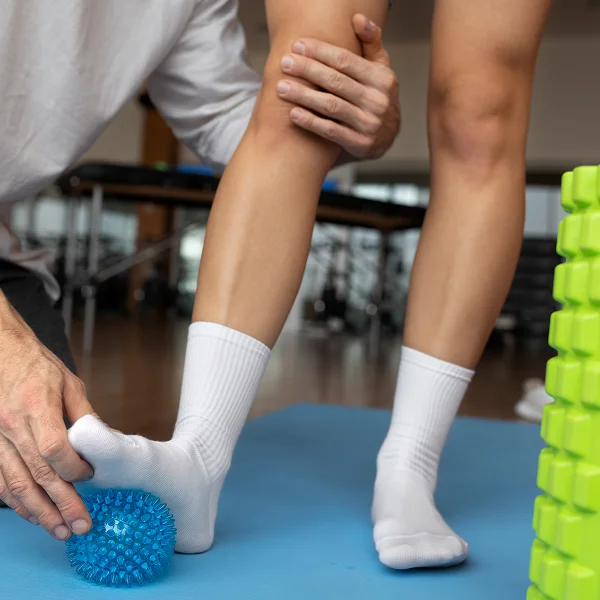 A person stretches their leg while holding a ball, demonstrating flexibility and balance in a fitness setting.