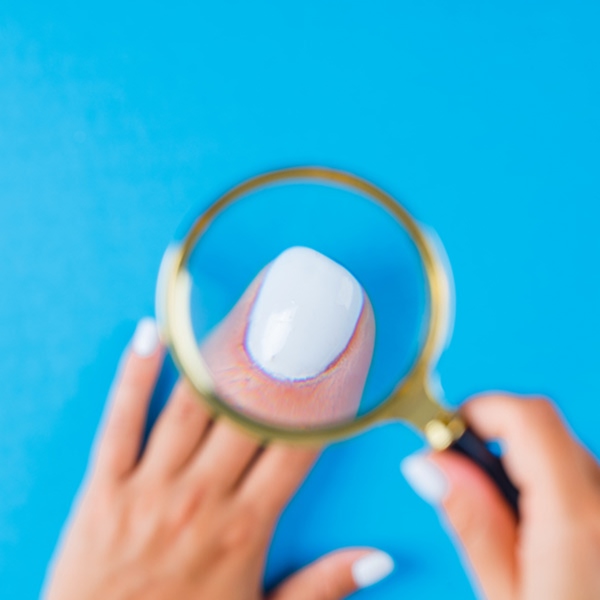 Healthy toenail under magnifying glass showing proper nail fungus prevention and foot hygiene