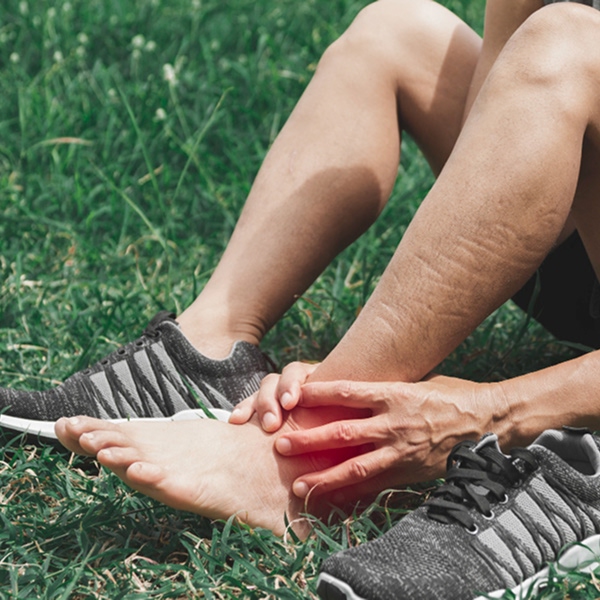 Person holding painful foot after activity illustrating need for osteoarthritis treatment in Laval